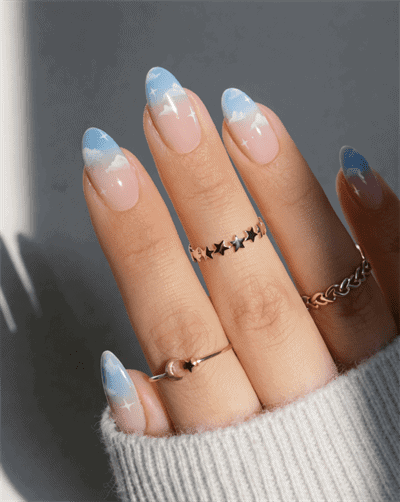 Soft blue ombre French tip nails with glossy finish and subtle star accents on natural almond-shaped nails