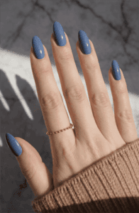 Dusty blue almond-shaped nails with glossy finish on long natural nails, minimalist solid color manicure in soft neutral tone