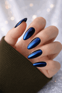 Metallic navy blue chrome almond nails with mirror finish on long elegant manicure against soft bokeh background