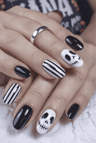 Black and white Halloween nails with skull art and striped design on glossy short almond nails, spooky nail art inspiration
