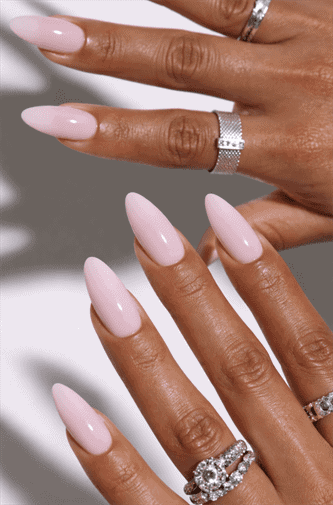 Long almond-shaped nails with soft milky pink nude polish, glossy finish with smooth high-shine surface, clean minimalist neutral manicure with elegant everyday aesthetic