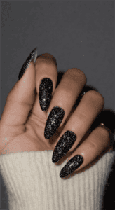 Long stiletto nails with black galaxy glitter polish, dense sparkling texture with multidimensional shimmer, bold night-sky inspired glam nail design