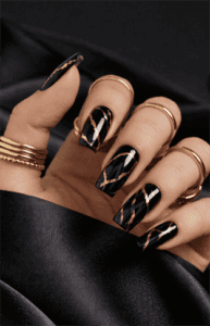 Coffin-shaped black nails with gold foil marble detailing, glossy luxury finish with abstract veining, bold high-end statement nail design