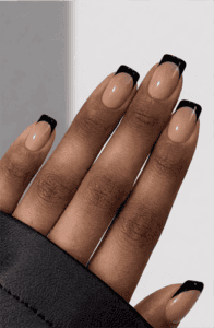 Long stiletto nails with nude base and sharp black edge French tips, minimalist negative space design with glossy finish and modern geometric accents