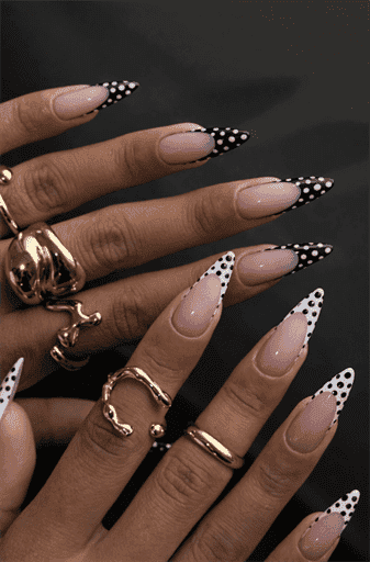 Long almond nails with nude base and black and white polka dot French tips, playful contrast design with glossy finish and trendy retro vibe