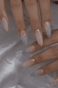 Long almond-shaped nails with sheer nude base and soft blue ombre tips, accented with delicate gold foil details, glossy finish and elegant airy gradient design