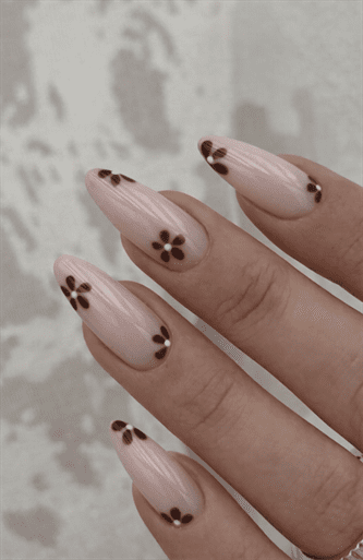 Almond-shaped nude nails with subtle vertical texture and small chocolate brown daisy flower accents, glossy finish with soft minimalist floral nail art
