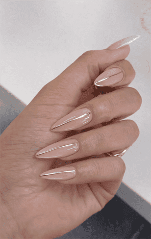 Long stiletto nails with nude base and thin gold line accents, sleek minimalist design with glossy finish and subtle luxury detail