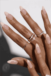 Long almond nails with soft nude base and subtle white French tips, glossy finish with natural minimal design and modern classic appeal