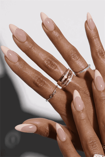 Long almond nails with soft nude base and subtle white French tips, glossy finish with natural minimal design and modern classic appeal