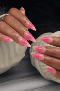 Long almond nails with neon pink aura gradient over nude base, soft blended glow effect with glossy finish and trendy vibrant summer nail design