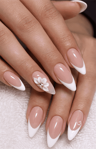 Almond-shaped nails with nude base and classic white French tips, featuring 3D floral accent with rhinestone center, glossy elegant bridal nail design