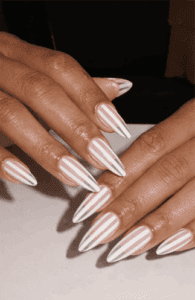 Long almond nails with nude base and vertical white stripe pattern, glossy finish with clean linear design and modern minimalist aesthetic
