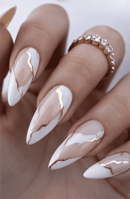 Almond-shaped nails with nude base and white marble French tips accented with gold detailing, glossy finish with luxury modern nail design