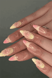 Pastel floral 3D almond nails with pink and yellow ombre tips, glossy nude base and sculpted flower nail art