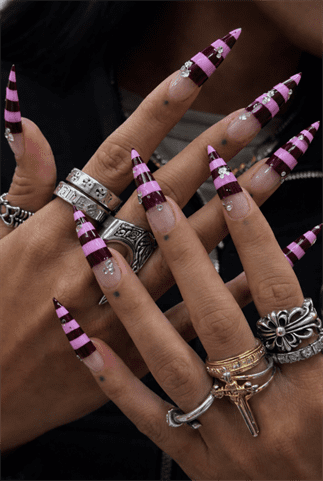 Pink and burgundy striped stiletto nails with glossy finish and rhinestone accents, long pointed statement nail design