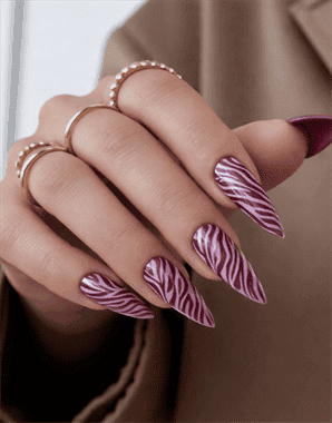 Purple zebra print stiletto nails with glossy finish, burgundy and white animal print nail art on long pointed nails