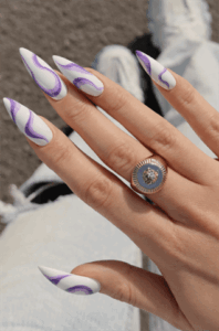 White and purple swirl stiletto nails with glossy finish, abstract wave nail art on long pointed nails