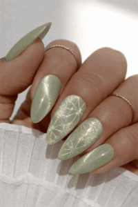 Sage green shimmer almond nails with glossy finish and subtle starburst nail art, elegant soft metallic manicure
