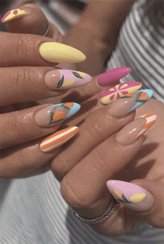 Colorful fruit nail art with pastel almond nails featuring lemons, oranges and striped designs on glossy nude base