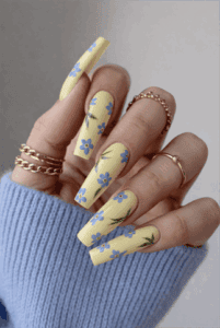 Yellow floral coffin nails with blue flower design, glossy long acrylic nails with spring nail art