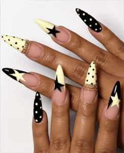 Black and butter yellow star stiletto nails with polka dot accents, retro graphic nail design on nude base