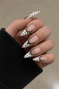 Black and white polka dot stiletto nails with bow accents, glossy coquette French tip nail design on nude base