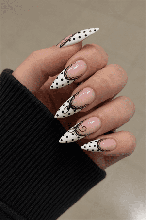 Black and white polka dot stiletto nails with bow accents, glossy coquette French tip nail design on nude base