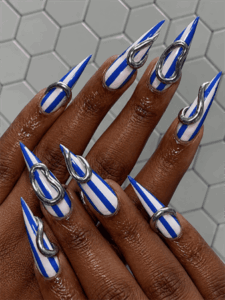 Blue chrome stripe stiletto nails with silver metallic 3D accents, bold futuristic nail design on long pointed nails
