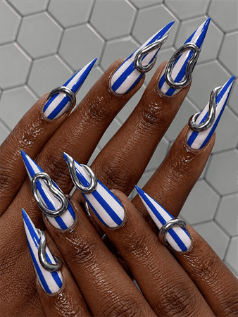 Blue chrome stripe stiletto nails with silver metallic 3D accents, bold futuristic nail design on long pointed nails