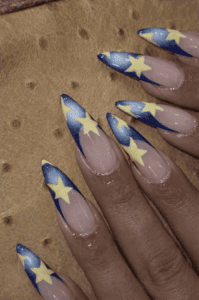 Blue star French tip stiletto nails with nude base, glossy celestial nail design with yellow star accents
