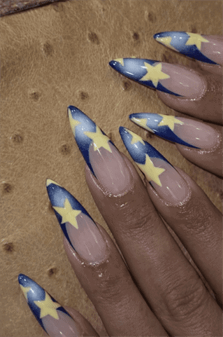 Blue star French tip stiletto nails with nude base, glossy celestial nail design with yellow star accents