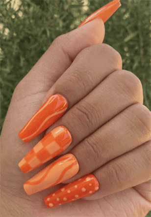 Bright orange mix and match coffin nails with checkerboard, swirl and polka dot nail art, glossy manicure
