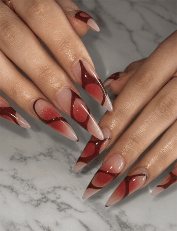 Burgundy aura stiletto nails with abstract swirl design, glossy nude base nail art on long pointed nails