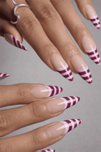 Burgundy and pink striped French tip stiletto nails with nude base, glossy long nail design