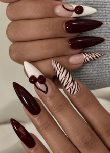 Deep cherry red stiletto nails with cream zebra print and glossy cherry nail art.
