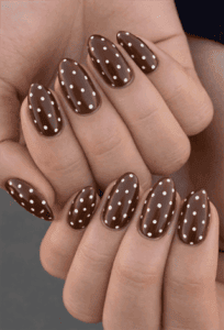 Chocolate brown polka dot almond nails with glossy finish, white dot nail design on long nails