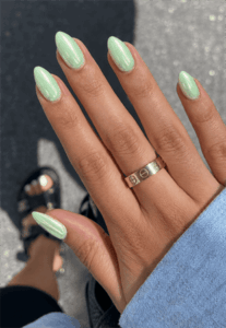 Glazed mint green almond nails with pearlescent chrome finish, glossy pastel nail design on medium-length almond nails