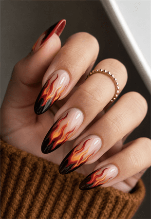 Molten flame almond nails with black smoky tips and fiery red orange flame nail art on nude base