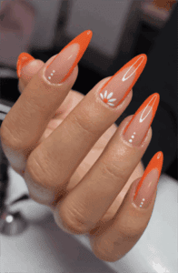 Neon orange French tip stiletto nails with daisy accent, glossy nude base bright floral nail design