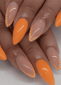 Orange French tip almond nails with polka dot outline, glossy nude base bright nail design”
