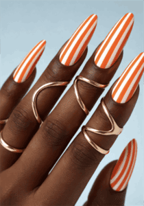 Orange and white striped stiletto nails with glossy finish, bold vertical stripe nail design on long nails