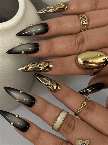Smoky black ombre stiletto nails with gold chrome accents, luxury gothic nail design featuring metallic 3D details