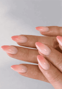Soft pink peach ombre almond nails with glossy finish, subtle gradient nude nail design on long nails