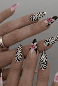 Zebra print almond nails with pink floral accents and black French tips, glossy animal print nail design