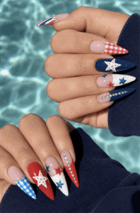 Patriotic patchwork stiletto nails featuring red, white and blue stars, gingham, pearls and glossy Fourth of July nail art on long pointed nails