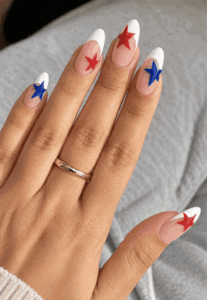 Patriotic star French tip almond nails with white tips, red and blue star nail art and glossy nude pink base