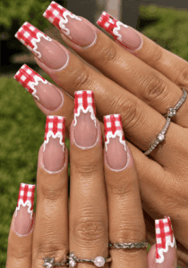 Red gingham French tip coffin nails with white drip accents, glossy picnic-inspired nail design on nude pink base