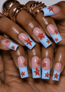 Baby blue French tip coffin nails with red star accents, glossy retro Americana nail design featuring gold stud embellishments