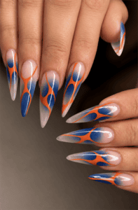 Blue and orange abstract flame stiletto nails with translucent nude base, glossy retro swirl nail art and modern statement manicure